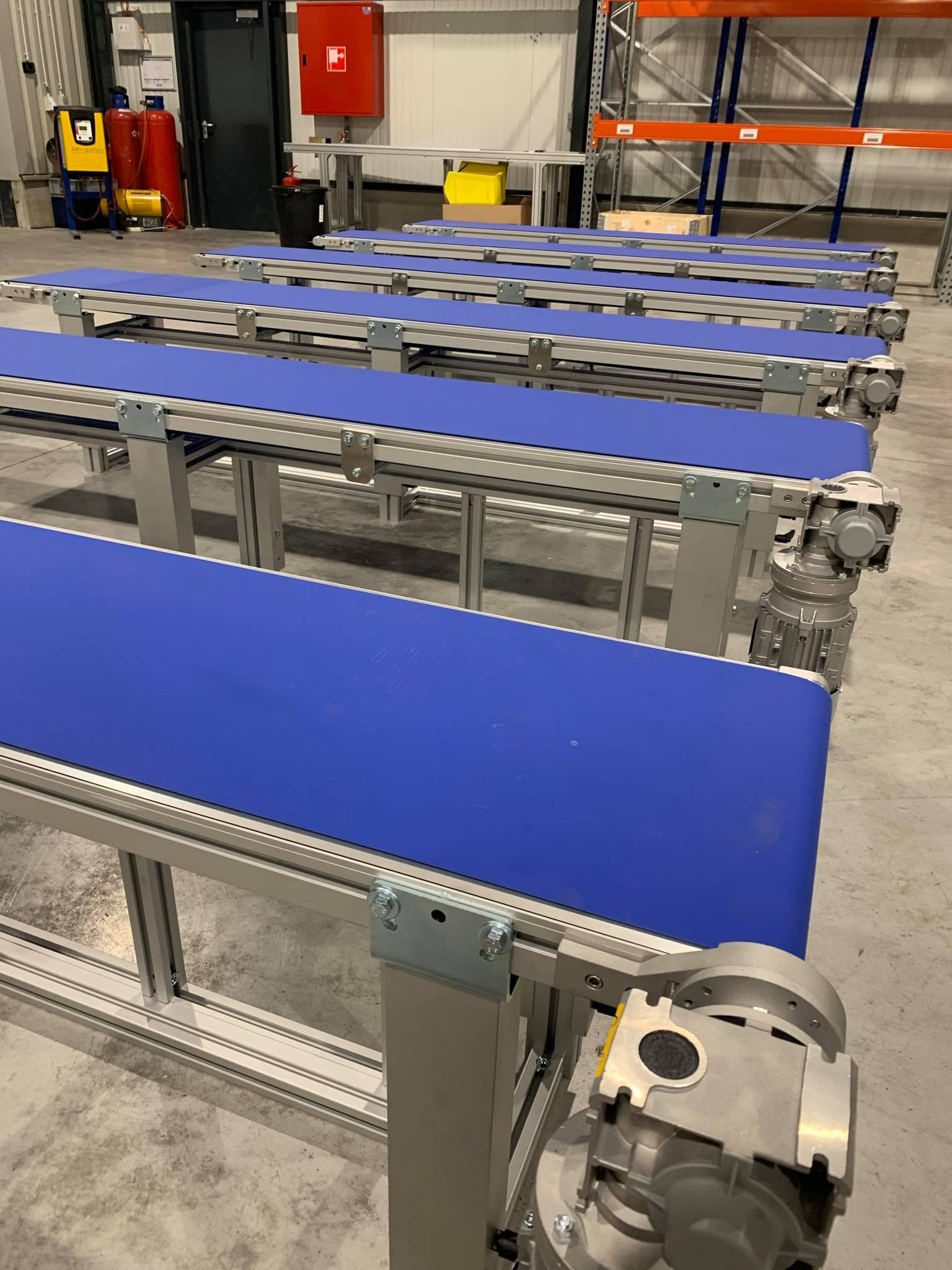 This is a setup of different flat conveyor belts, lined up next to each other in a warehouse or production environment.